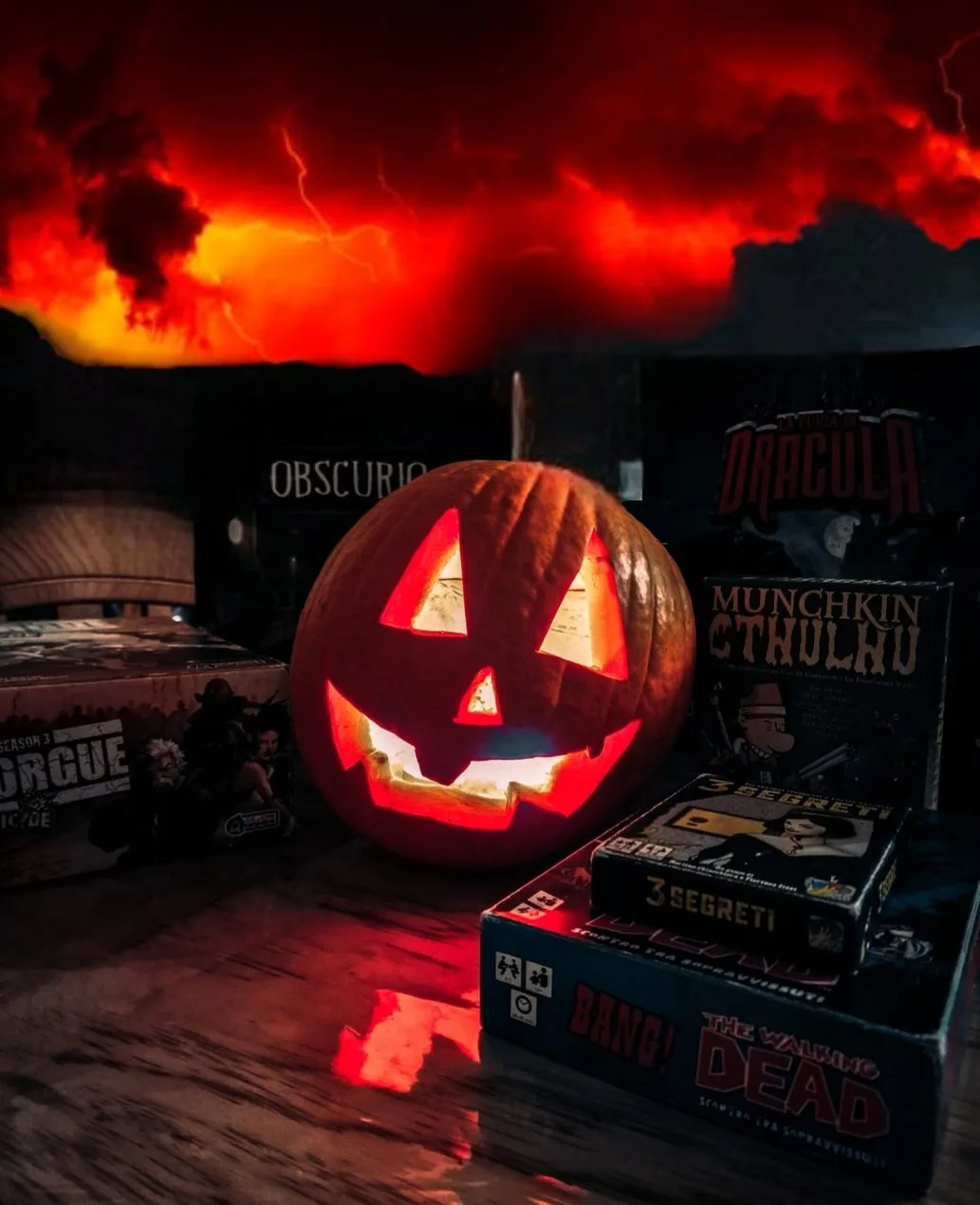 Una zucca intagliata illuminata tra i giochi da tavolo horror